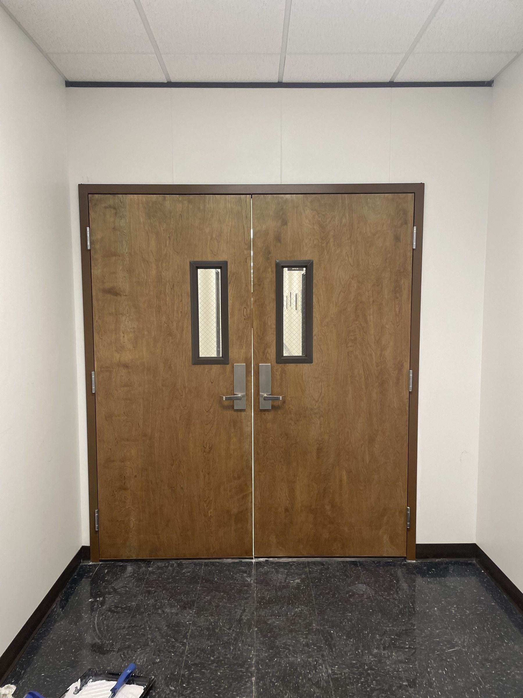 Wood double doors with narrow vision lites in a hallway
