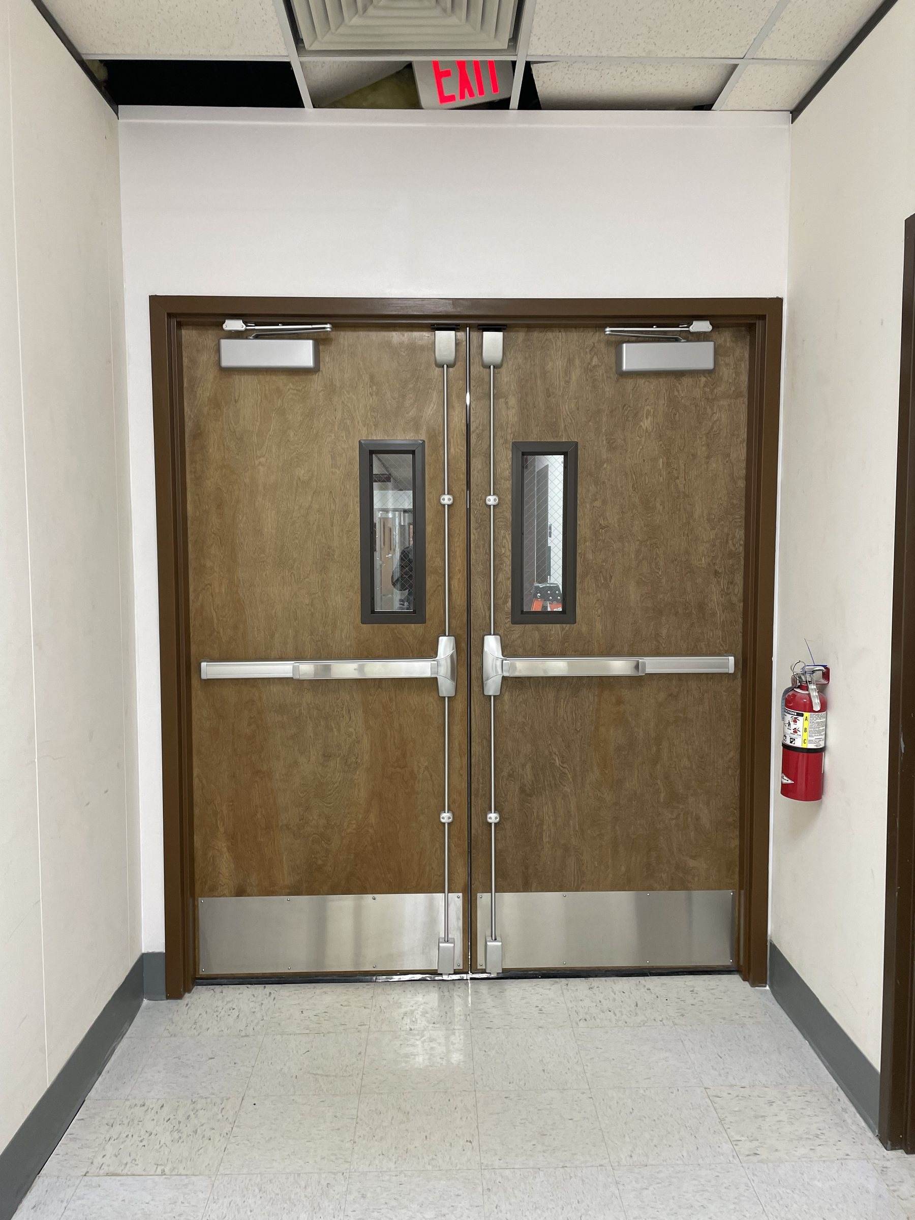 Wood double doors with vertical rod panic bars and closers
