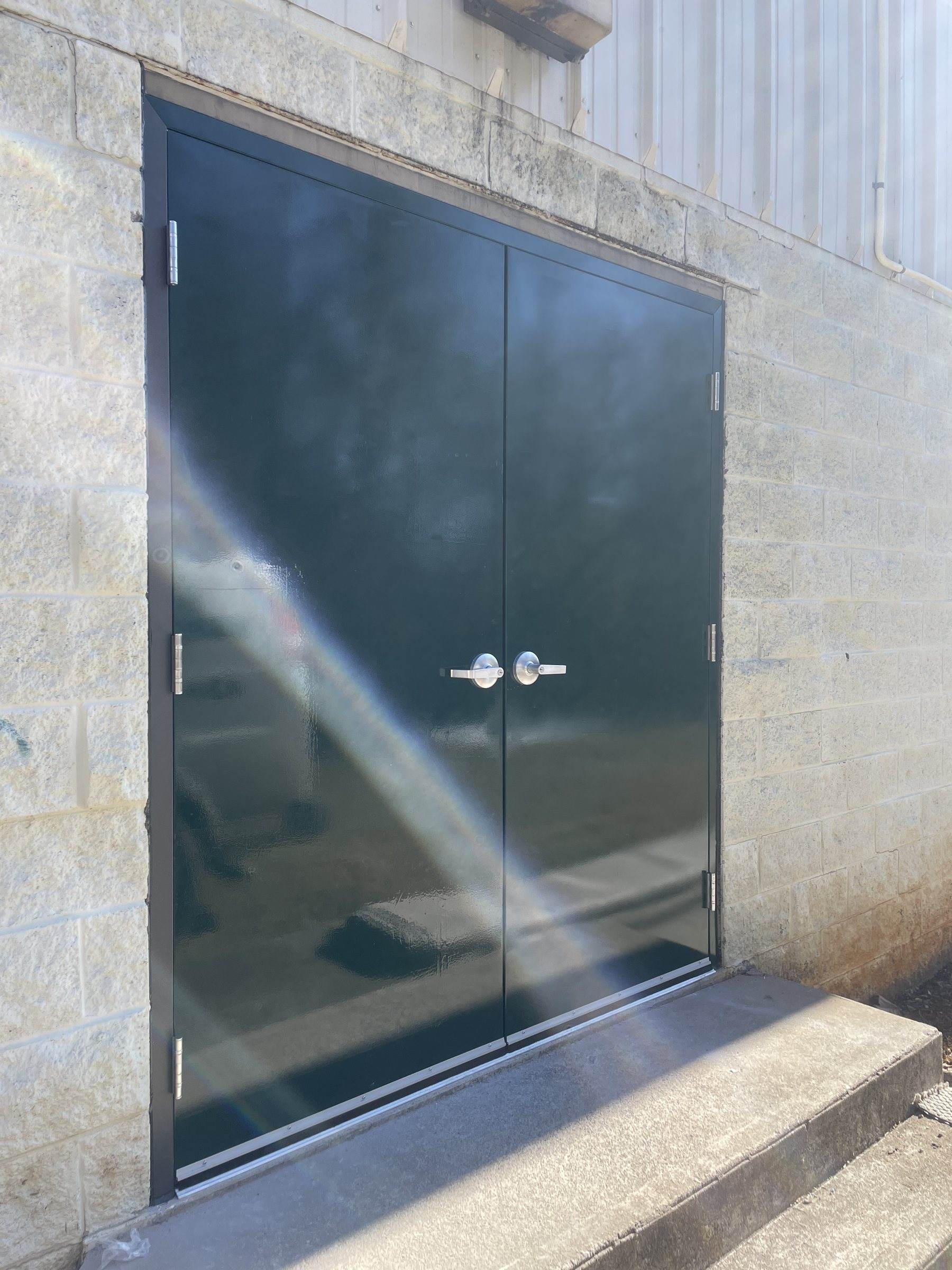 Dark hollow metal double doors in a block wall