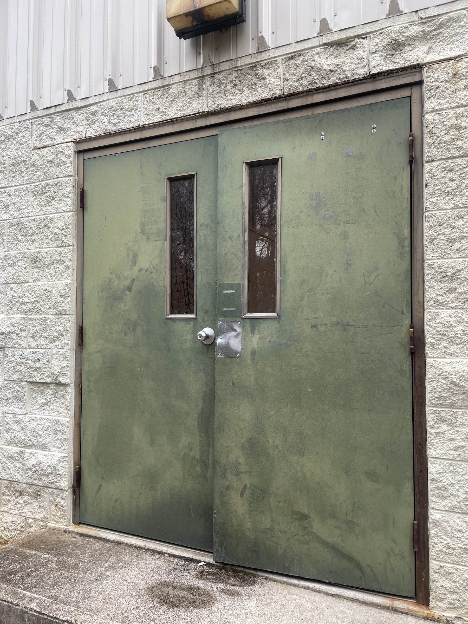 Green steel double doors with vision lites at a side entrance