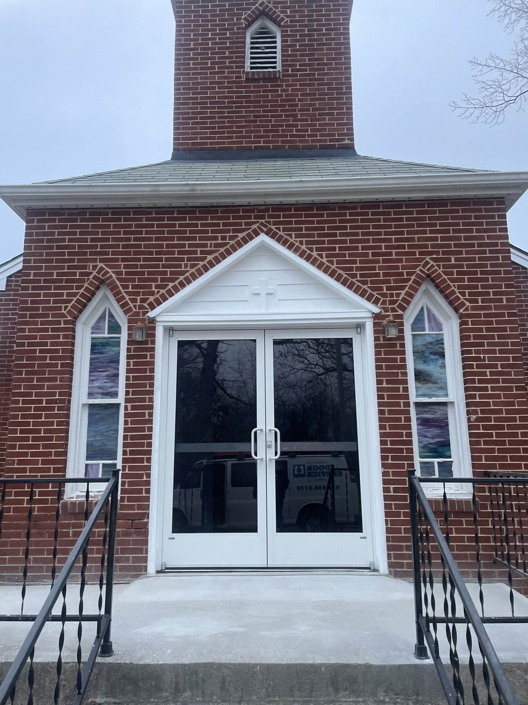 White double entry doors in a brick church entrance with a steeple above
